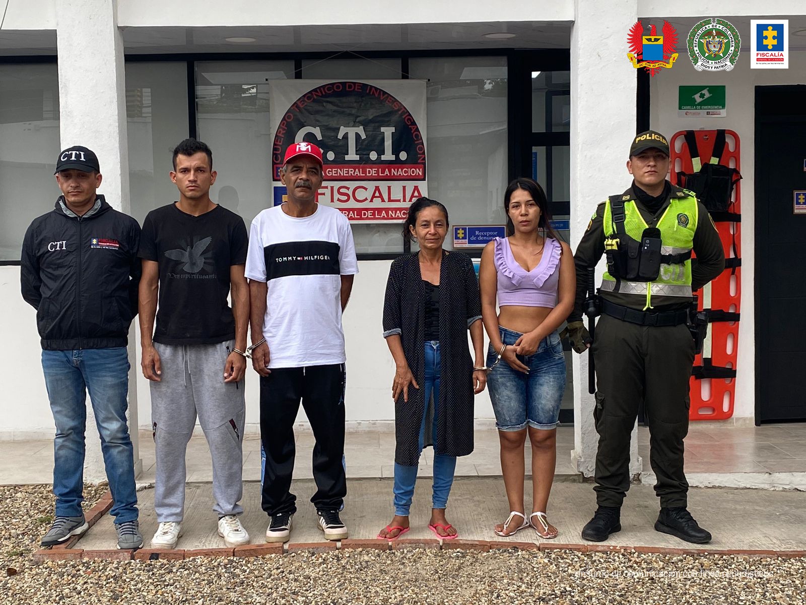 en la imagen se ven varias personas detenidas en custodia de la Policía, CTI y Fuerza Aérea. Detrás suyo backings de las dos últimas instituciones.
