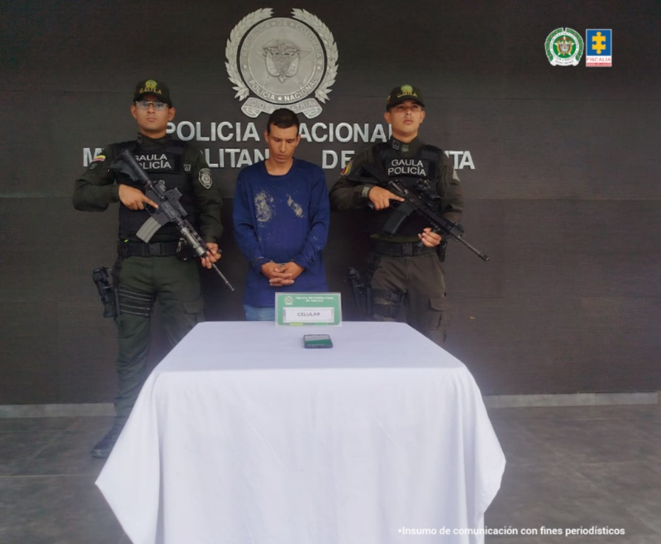 Se visualiza al capturado junto a dos uniformados del Gaula de la Policía Nacional. Detrás de ellos el banner que identifica a la Policía Metropolitana de Cúcuta.