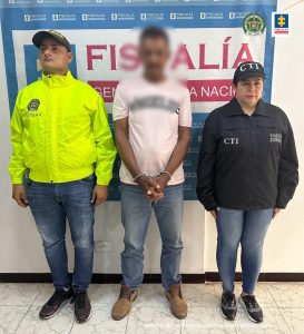 capturados de frente custodiados por investigador del CTI de la Fiscalía y Policía. Detrás banner de Fiscalía.