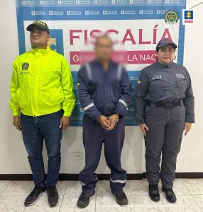 capturados de frente custodiados por investigador del CTI de la Fiscalía y Policía. Detrás banner de Fiscalía.