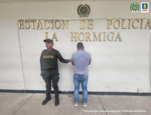 en la imagen se ve una persona detenida de espaldas, bajo custodia de dos uniformados de la Policía Nacional.