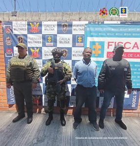 En la imagen se ve una persona detenida bajo custodia de integrantes del CTI de la Fiscalía y del Ejército Nacional. Detrás suyo backings institucionales.