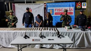 En la fotografía aparecen dos capturados, junto a personal de Fiscalía General de la Nación y Ejercito Nacional. En la parte posterior de la imagen se ven banners de Ejercito Nacional y la Fiscalía General de la Nación.     