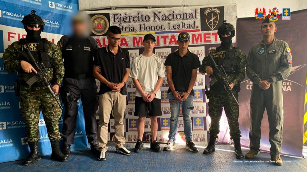 Capturados de frente custodiados por investigador CTI de la Fiscalía y militares de la Fuerza Aérea y del Ejército Nacional. Detrás banner de la Fiscalía y del grupo Gaula Militar Meta.