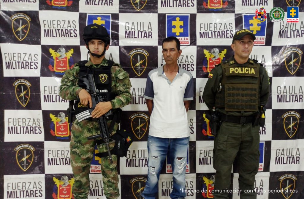 El imputado, se encuentra en custodia por un uniformado del Gaula del Ejército y Policía Nacional. Detrás se observa un backing del Ejército.