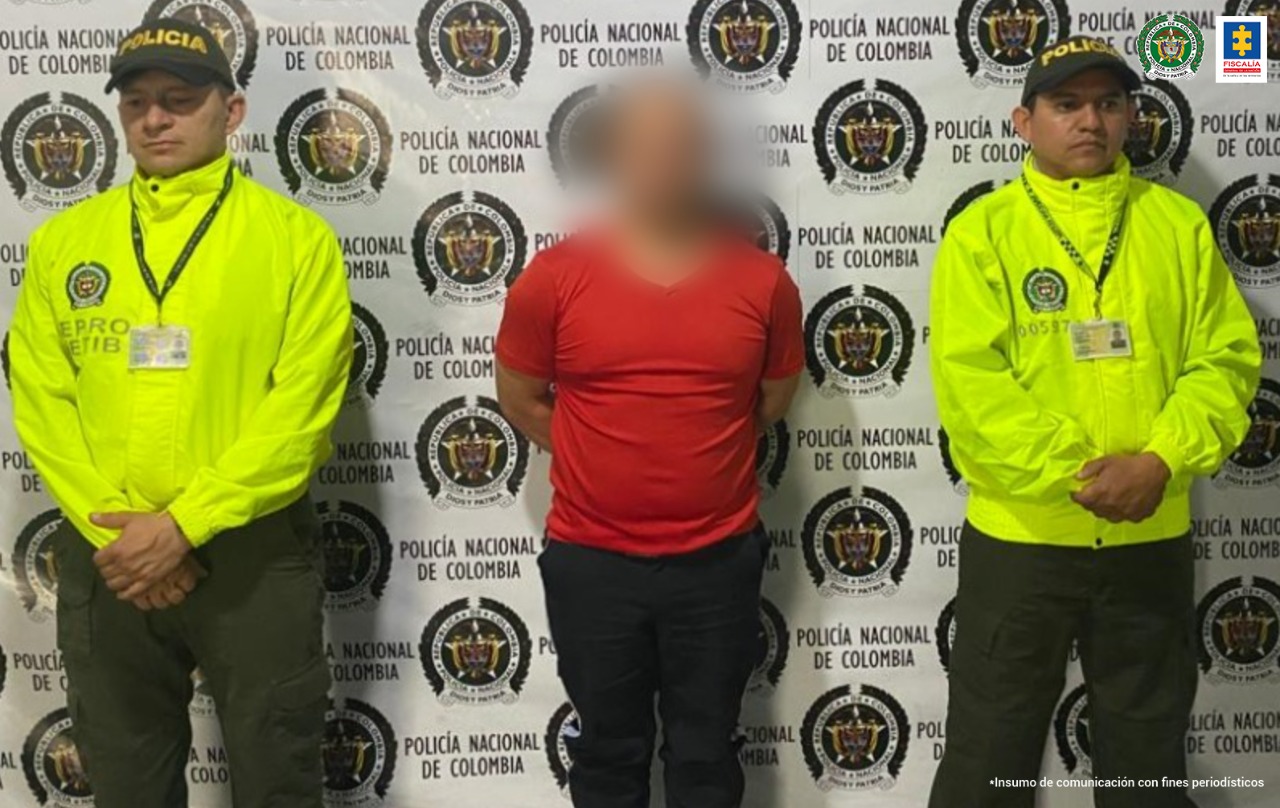 En la imagen se ve una persona detenida bajo custodia de la Policía. Detrás suyo un backing de la institución.