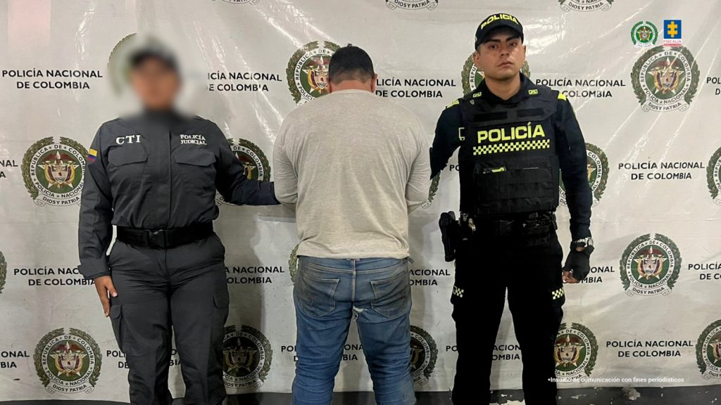 en la imagen se ve una persona detenida de espaldas, bajo custodia de un investigador del CTI y un uniformado de la Policía Nacional.