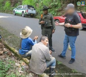 se ven dos personas detenidas mientras las autoridades les leen sus derechos.