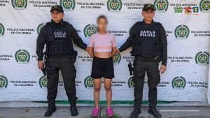 En la imagen se ve una mujer detenida bajo custodia de integrantes de la Policía Nacional.