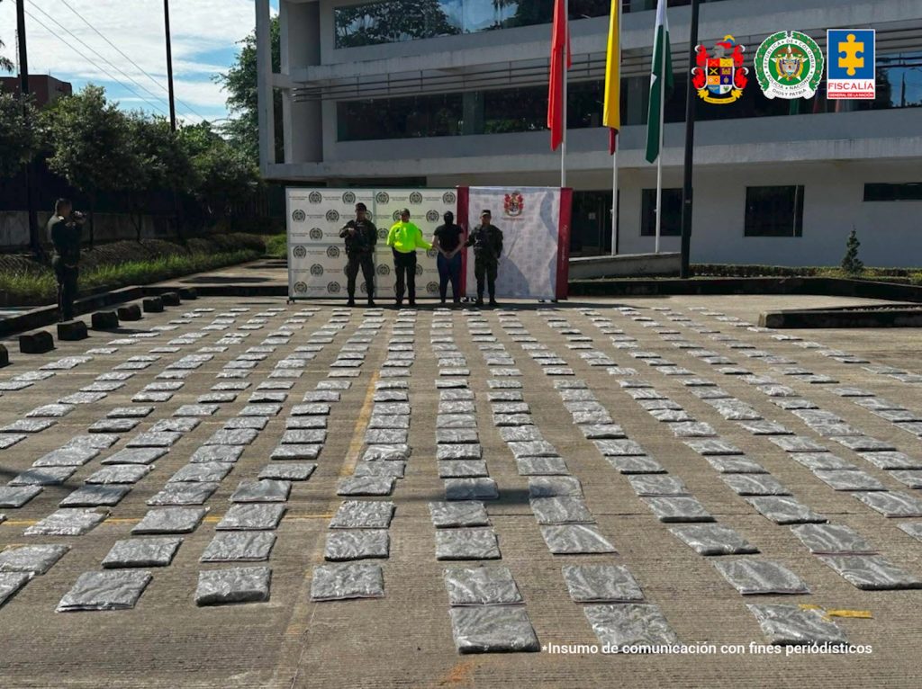 En la imagen se ve una mujer detenida bajo custodia de un integrante de la Policía y el Ejército con varias dosis de estupefacientes en el suelo.