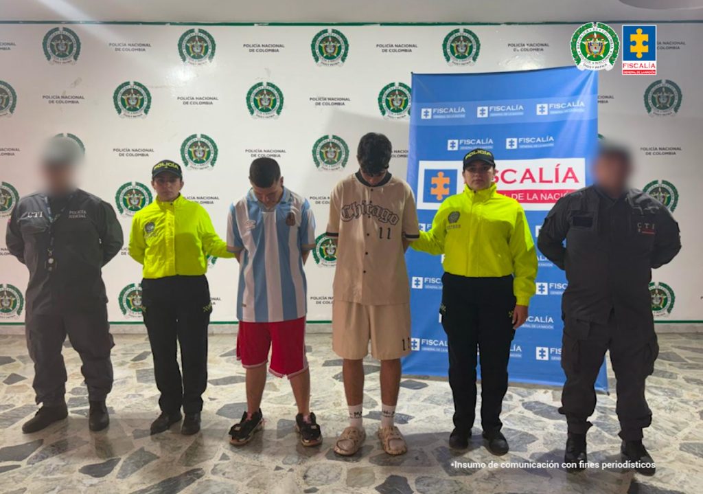 En la imagen se ven dos personas detenidas bajo custodia de investigadores del CTI y de la Policía Nacional. Detrás suyo un backing institucional.