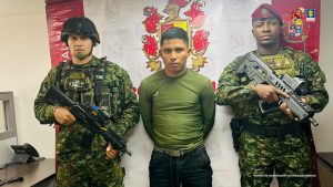 En la imagen se ve una persona detenida bajo custodia de integrantes del Ejército Nacional. Detrás suyo un backing institucional.