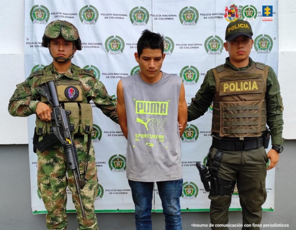 En la imagen se ve una persona detenida bajo custodia de dos uniformados de la Policía Nacional.