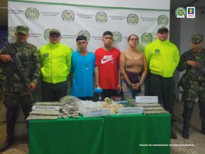 Se observan los tres detenidos y a cada lado dos uniformados de la Policía Nacional. Al fondo pendón de Policía Nacional