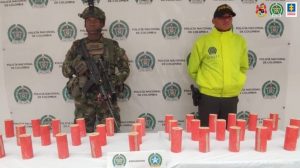 En la fotografía aparecen los explosivos junto a un agente de la Policía Nacional y un soldado del Ejército Nacional.   En la parte posterior hay un banner de la Plicìa Nacional.