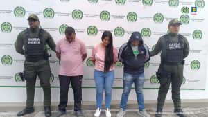  en la imagen se ven tres personas detenidas bajo custodia de dos uniformados de la Policía.