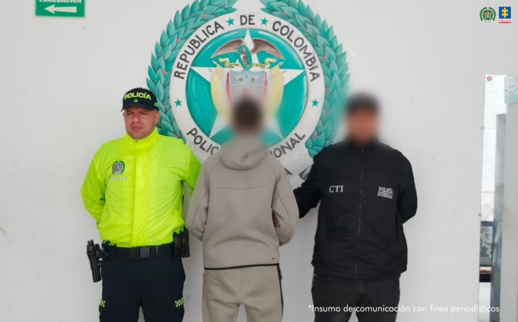 En la imagen está el adolescente aprehendido de espaldas en medio de un servidor del CTI y otro de la Policía