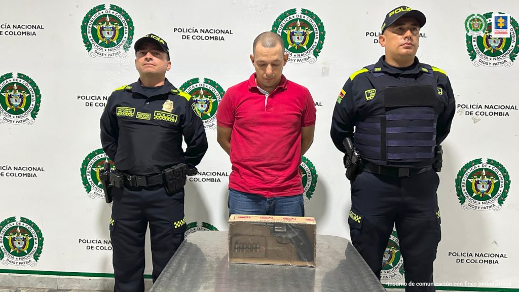 en la imagen se ve un hombre detenido bajo custodia de dos uniformados de la Policía Nacional.