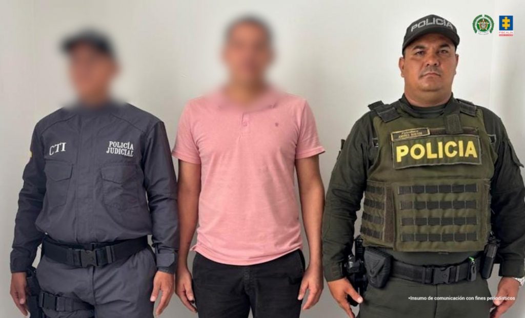 en la imagen se ve un hombre detenido bajo custodia de un integrante de la Policía Nacional y un investigador del CTI.