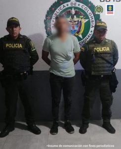 En la fotografía se observa a un hombre de pantalón negro con camiseta verde clara y zapatos negros, custodiado por dos agentes de la Policía Nacional.