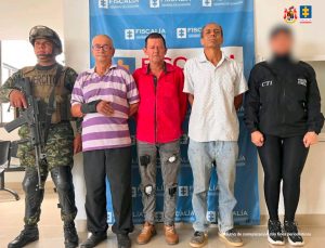En la fotografía aparecen los tres capturados junto a un soldado del Ejército y un servidor del CTI. En la prte superior está un banner de la Fiscalía General