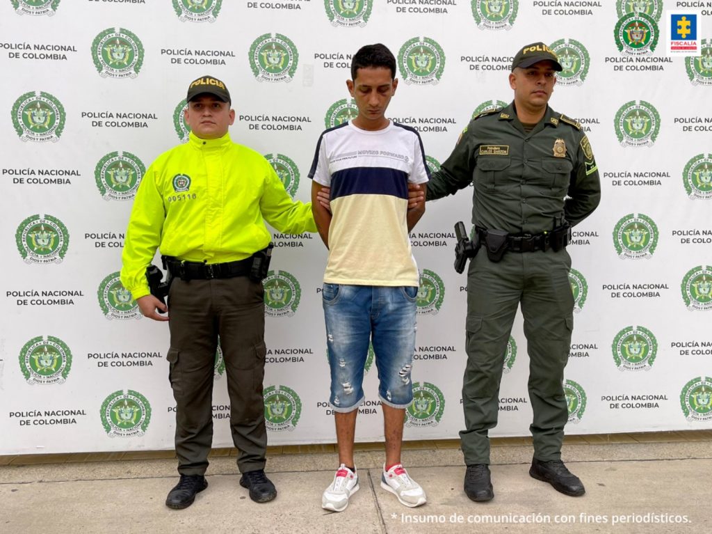 en la imagen se ve una persona detenida bajo custodia de dos uniformados de la Policía Nacional.