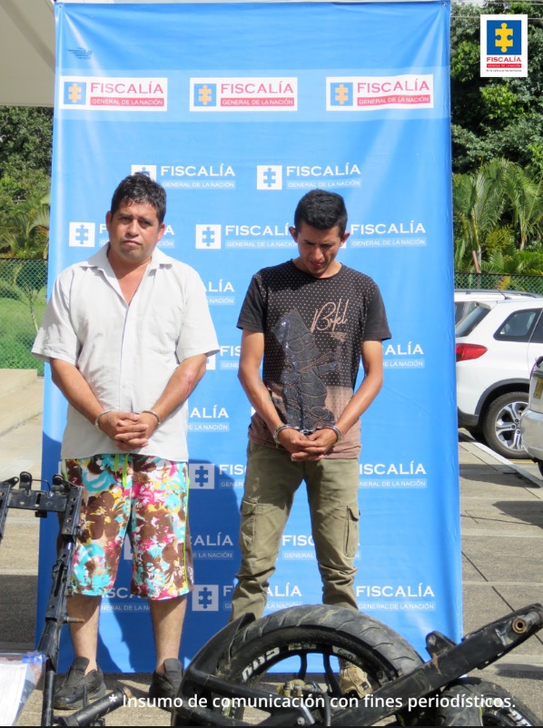 En la imagen se ven dos personas detenidas. Detrás suyo un backing de la Fiscalía..