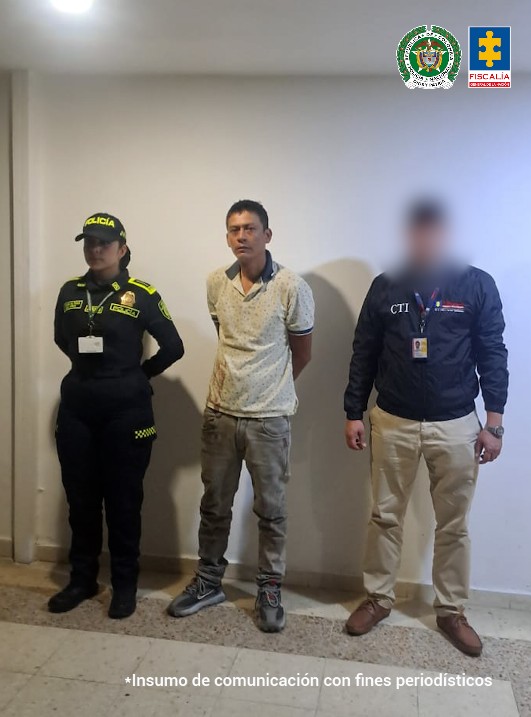 en la imagen se ve una persona detenida bajo custodia de un investigador del CTI y de un uniformado de la Policía Nacional.