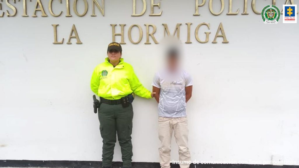 En la fotografía aparece un capturado, junto a personal de Policía Nacional. En la parte posterior de la imagen se ven banners de Policía Nacional y la Fiscalía General de la Nación.