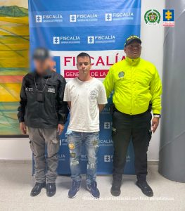 en la imagen se ve un hombre detenido bajo custodia de un integrante del CTI y otro de la Policía Nacional.