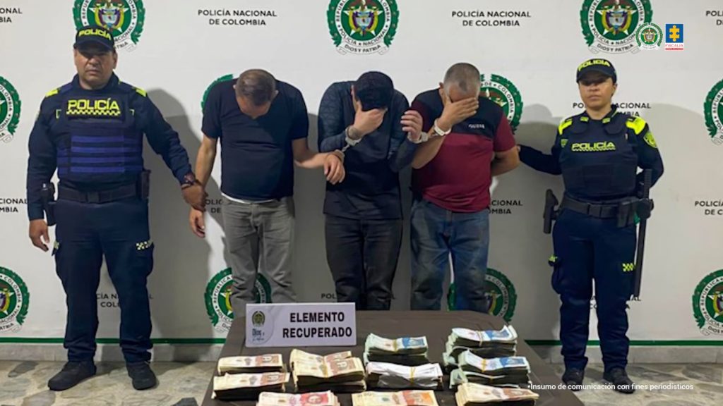 En la imagen se ven tres personas detenidas bajo custodia de dos uniformados de la Policía Nacional 