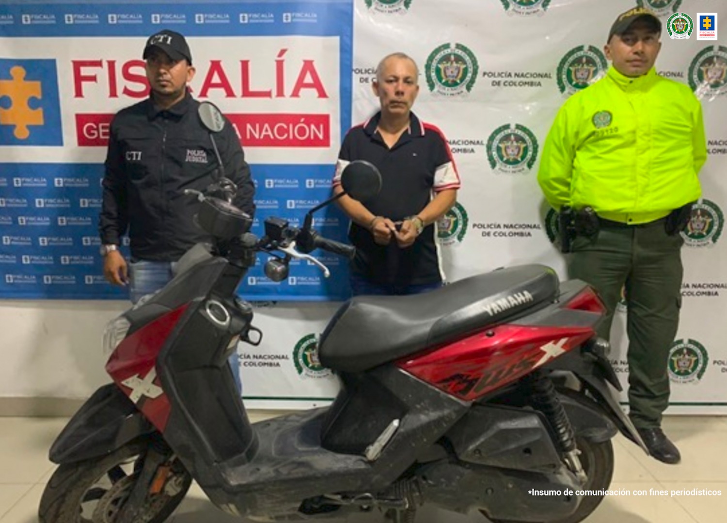 En la imagen se ve una persona detenida bajo custodia de la Policía y el CTI de la Fiscalía. Detrás suyo un backing de ambas instituciones. Delante de ellos una motocicleta recuperada la cual había sido hurtada.