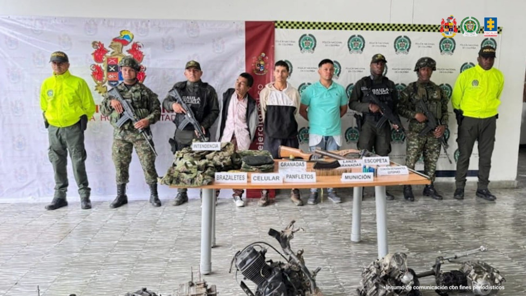 En la fotografía aparecen los tres capturados junto a un servidor del CTI, tres uniformados de la Policía Nacional y dos soldados del Ejército. En la parte posterior están un mesa con armas, munición, explosivos, seis motores para motocicletas y placas.