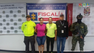 Se visualiza a los capturados junto a investigador del CTI y uniformados de la Policía y Ejército Nacional. Detrás de ellos los banners que identifican a la Fiscalía General de la Nación y a la Policía y Ejército Nacional.