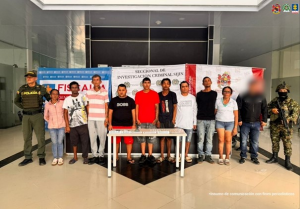 Se observa a los capturados junto a un investigador del CTI y uniformados de la Policía y Ejército Nacional. Frente a ellos los banners que identifica a la Fiscalía General de la Nación a la Policía y Ejército Nacional.