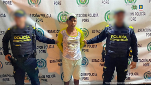 Se visualiza al capturado junto a dos uniformados de la Policía Nacional. Detrás de ellos el banner que identifica a la Policía Nacional.