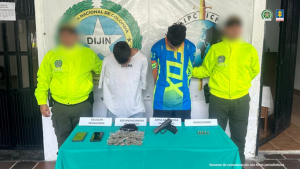 Se observa a los dos capturados junto a uniformados de la Policía Nacional. Frente a ellos los elementos incautados (armas y sustancias estupefacientes). Detrás el banner que identifica a la Policía Nacional.