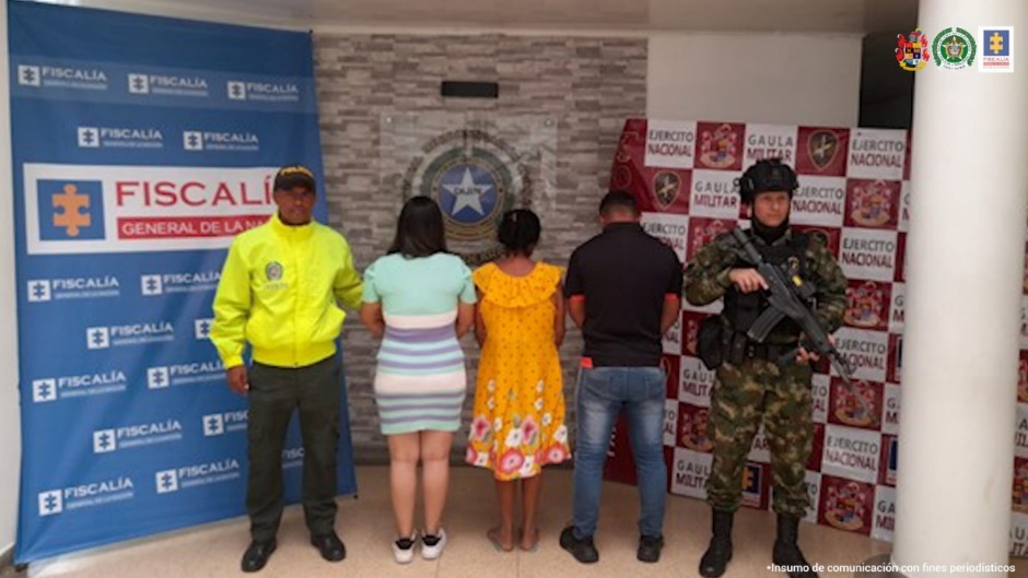 En la imagen se visualizan tres capturados junto a uniformados de la Policía y Ejército Nacional. En la parte posterior se encuentran los banners de la Fiscalía General de la Nación y Ejército Nacional.