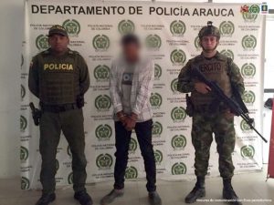 En la fotografía aparece el procesado junto a uniformados de la Policía y del Ejército Nacional. En la parte posterior se aprecia el banner que identifica al Departamento de Policía de Arauca.