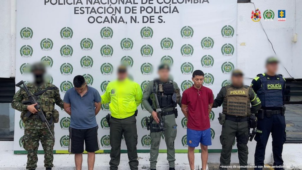 Se visualiza a los capturados junto a uniformados del Ejército y Policía Nacional. Detrás de ellos el banner que identifica a la Policía Nacional