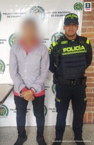 En la imagen se aprecia el capturado junto a un uniformado de la Policía Nacional. En la parte posterior se observa el banner que identifica a la Policía Nacional.