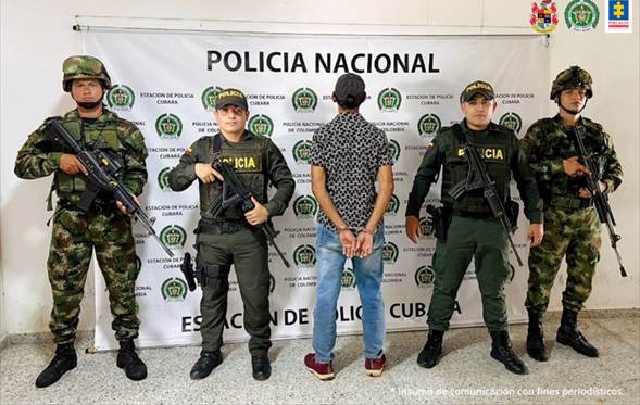 En la fotografía se aprecia al capturado de espaldas junto a uniformados del Ejército y Policía Nacional. Detrás de ellos se visualiza el banner que identifica a la Policía Nacional.