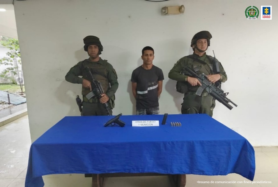En la imagen se aprecia al capturado junto a dos uniformados de la Policía Nacional. Al frente en una mesa se observa la pistola y munición incautada.