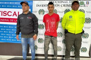 En la fotografía aparece el capturado junto a un investigador del CTI y uniformado de la Policía Nacional. Detrás se observa los banners que identifican a la Fiscalía y a la Policía Nacional