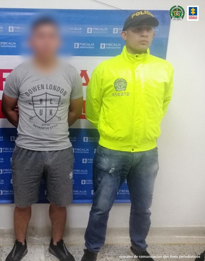 En la fotografía aparece el capturado con el rostro difuminado junto a un integrante de la Sijin. En la parte posterior se observa el banner que identifica a la Fiscalía General de la Nación.