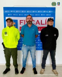 En la fotografía aparece el capturado junto un investigador del CTI y de la Sijin. En la parte posterior se aprecia el banner que identifica a la Fiscalía General de la Nación