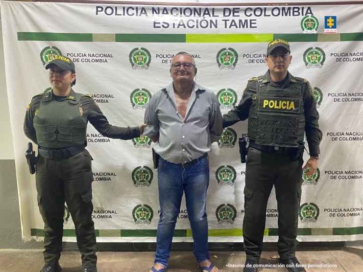 Se visualiza al capturado junto a dos uniformados de la Policía Nacional. Detrás el banner que identifica a la Estación de Policía de Tame (Arauca)