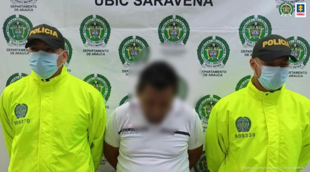 En la imagen se observa el capturado junto a dos uniformados de la Policía Nacional. En la parte posterior el banner que identifica a la Policía Nacional.