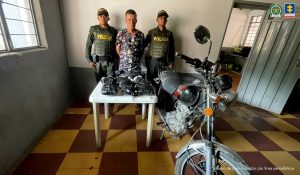 En la imagen se observa al capturado junto a dos uniformados de la Policía Nacional. Frente a ellos la sustancia alucinógena incautada y la motocicleta.