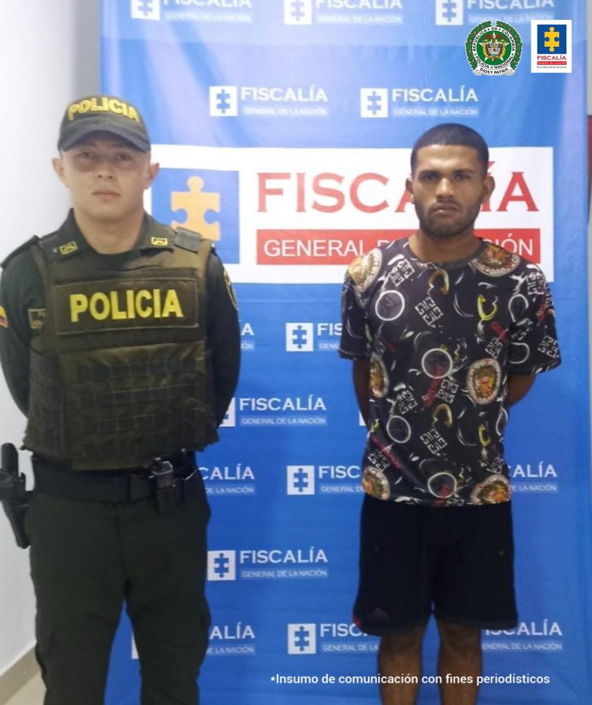 En la imagen se observa al capturado junto a uniformado de la Policía Nacional. Detrás de ellos se encuentra el banner que identifica a la Policía Nacional.